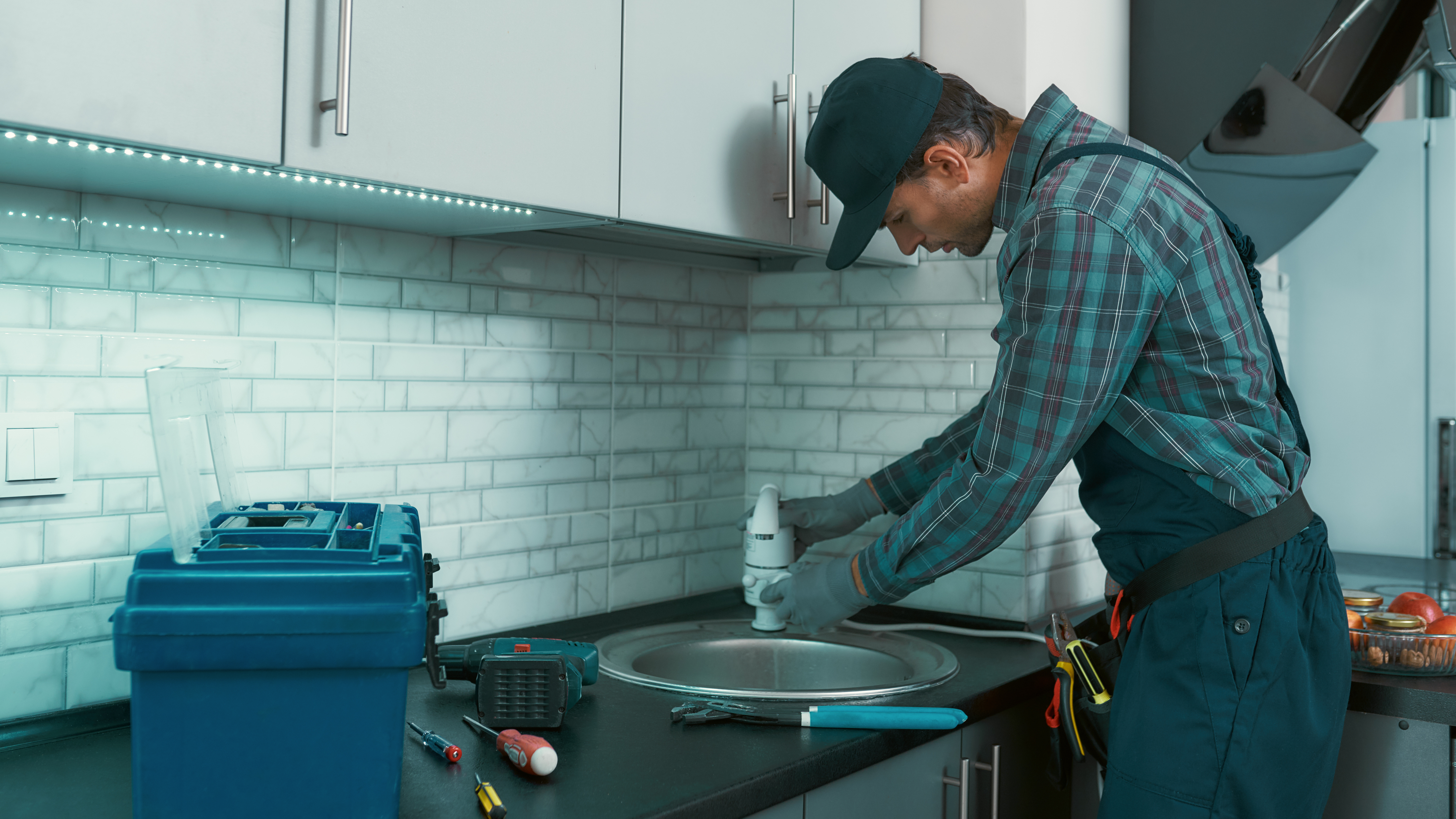 Man cleaning the kitchen sink faucet aerator for better water flow and quality.