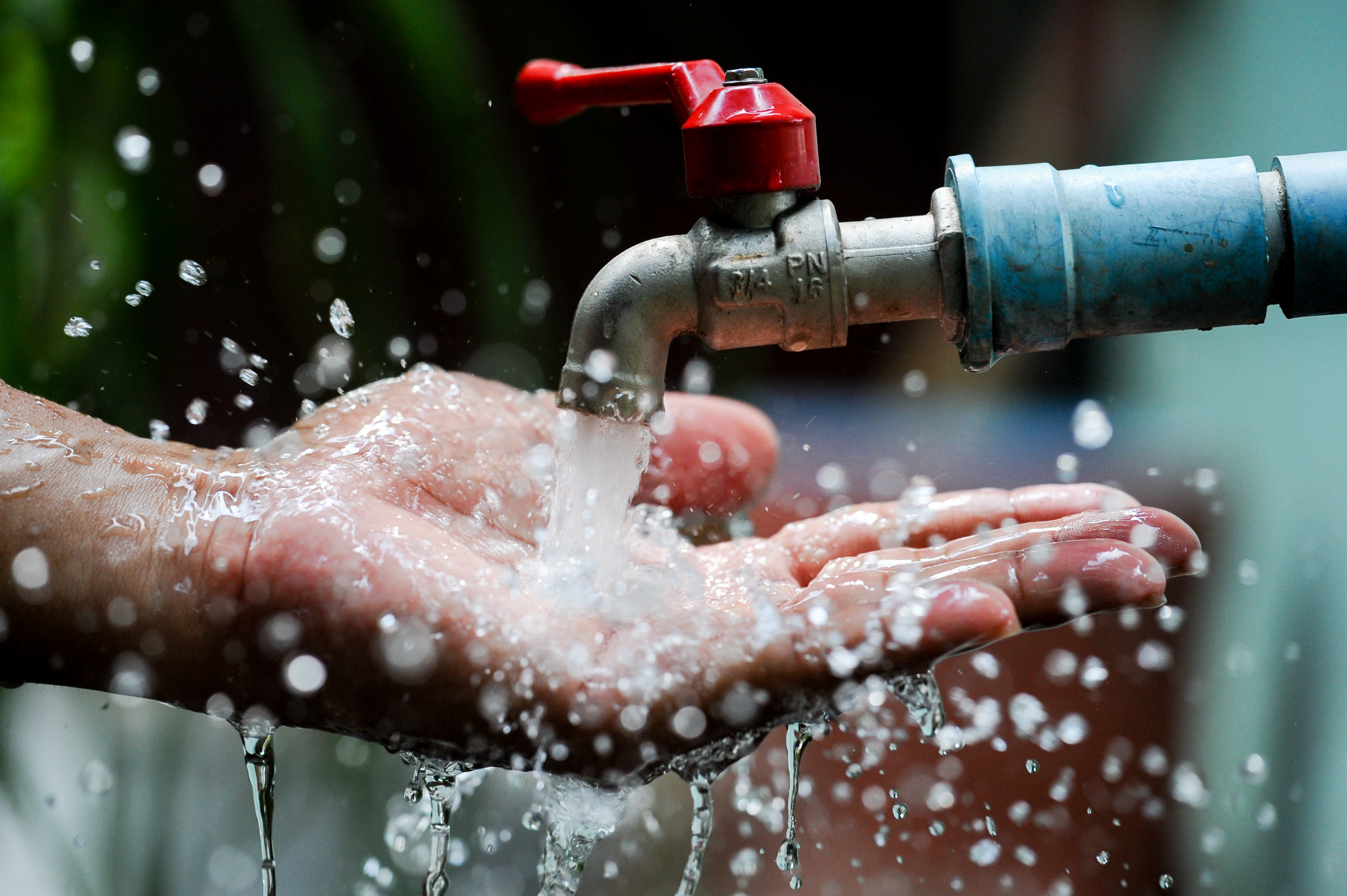 Outside water faucet producing soft filtered water into someone’s hands