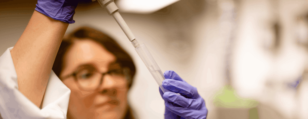 gloved woman testing water in a lab for st108 compliance