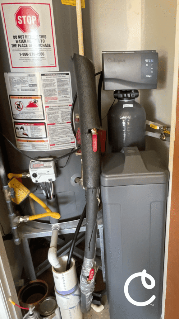 culligan water softener in a small garage closet next to a water heater