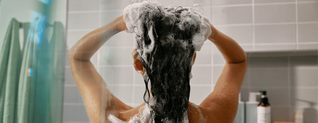 woman washing hair with shampoo in shower